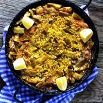 veggie paella in a black pan on a wooden table
