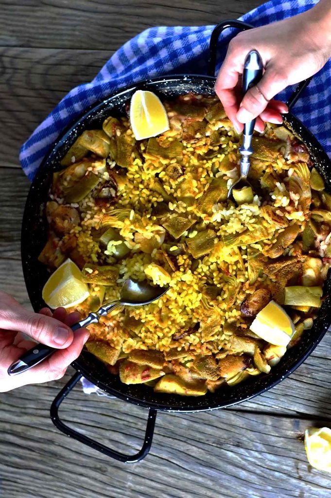Two people eating from a paella in a pan