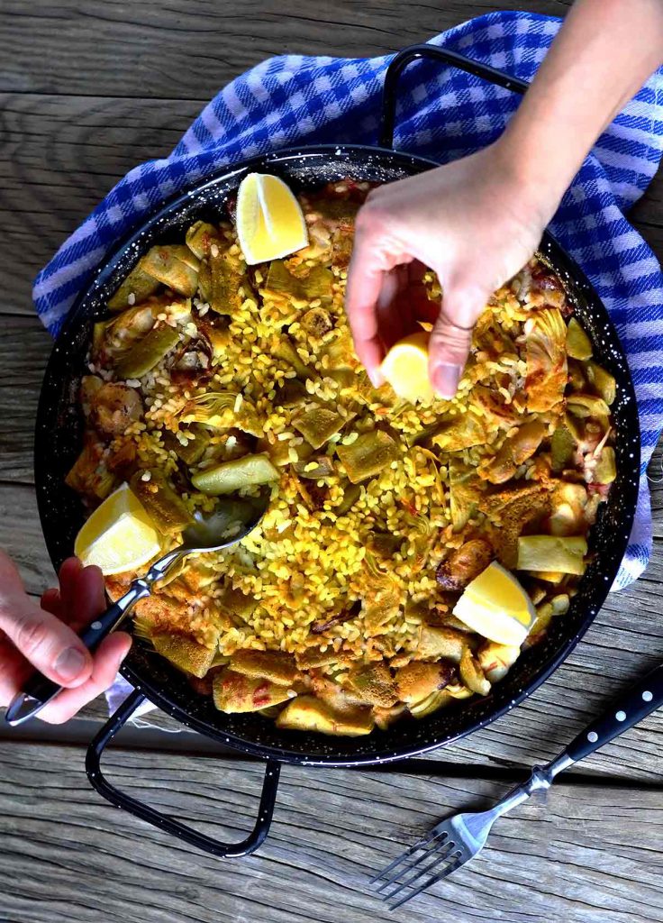 Two people eating from a paella in a pan