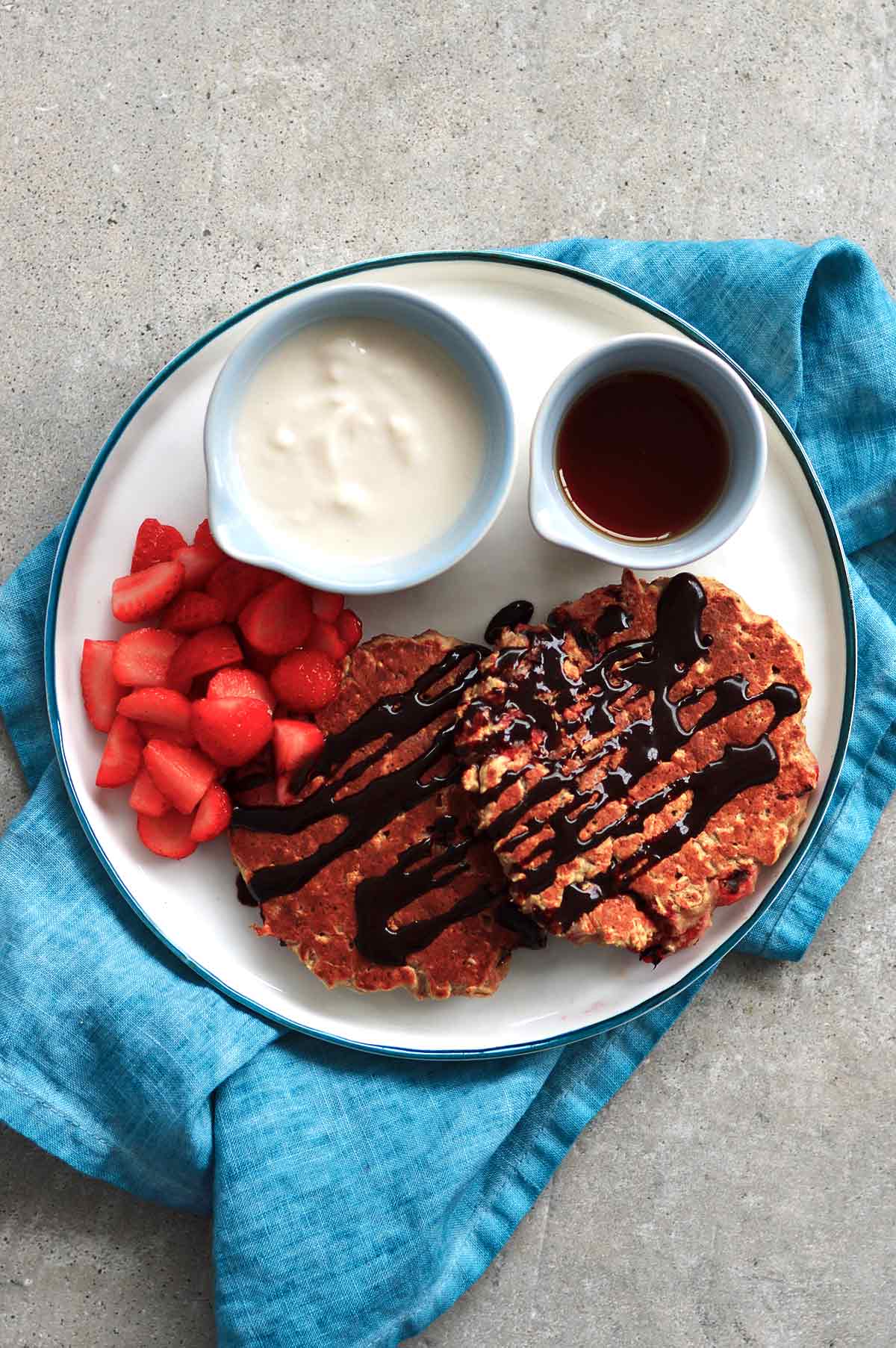 Strawberry and oatmeal pancakes served with maple syrup, yogurt and chopped strawberries