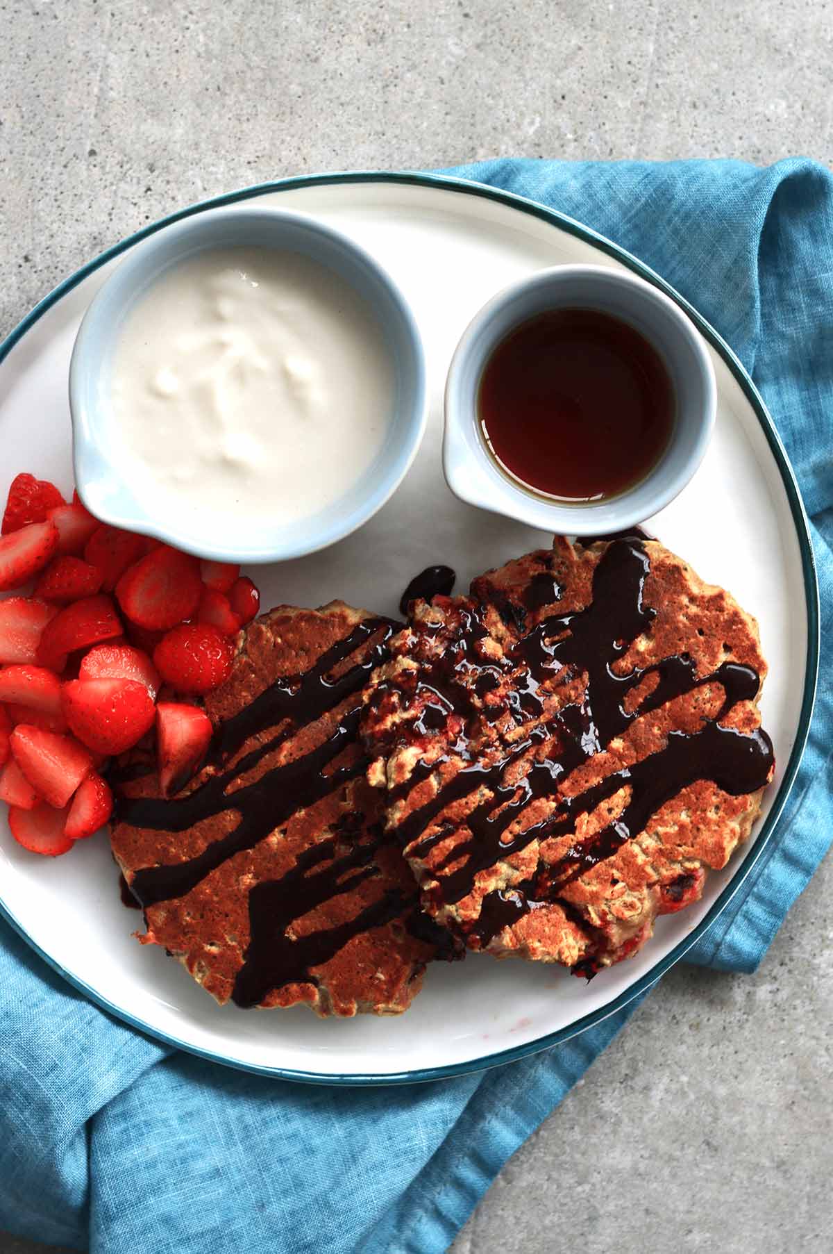 Strawberry and oatmeal pancakes served with maple syrup, yogurt and chopped strawberries