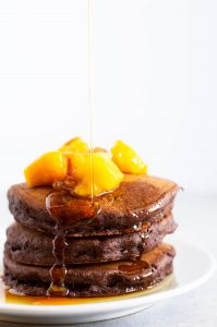 vegan chocolate pancakes drizzled with maple syrup